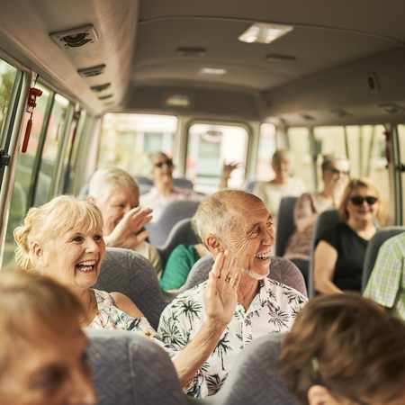 A group of retirees sitting on a bus and smiling