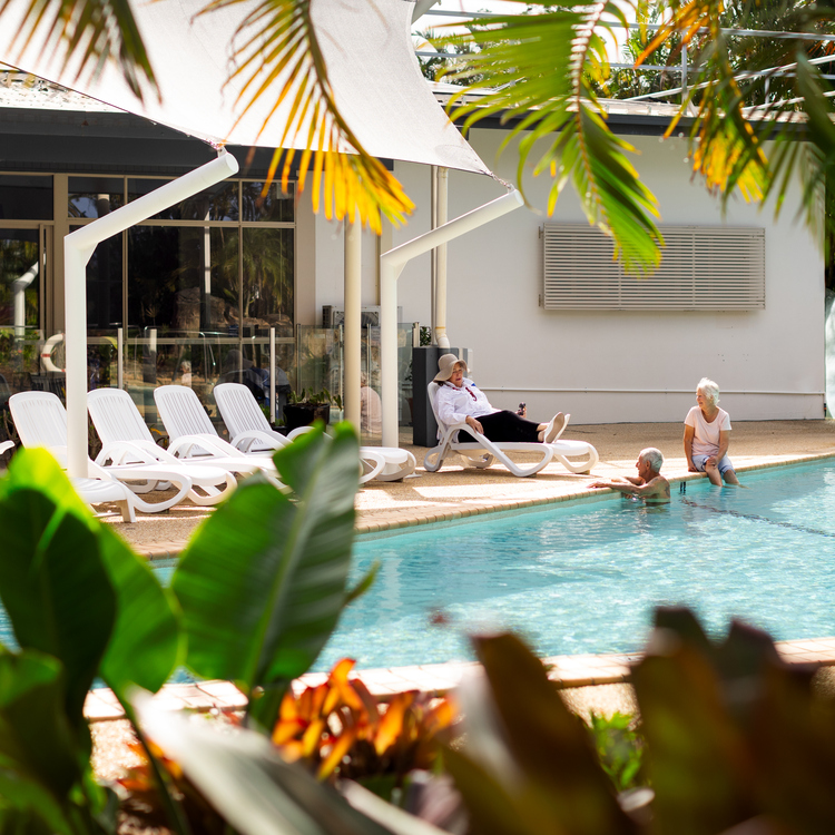 A couple of senior residents enjoying an outside pool on a sunny warm day.