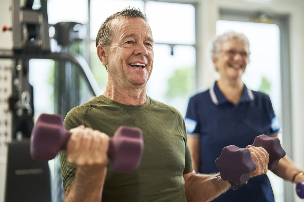  A senior man at the gym exercising with dumbells