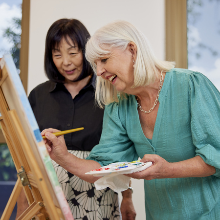 Woman painting while another lady is looking on
