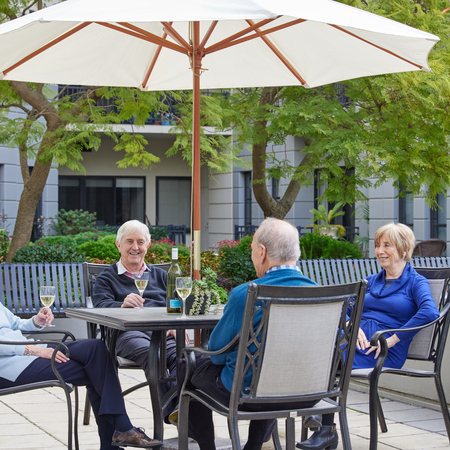 Four seniors sitting at an outside table enjoying a glass of wine