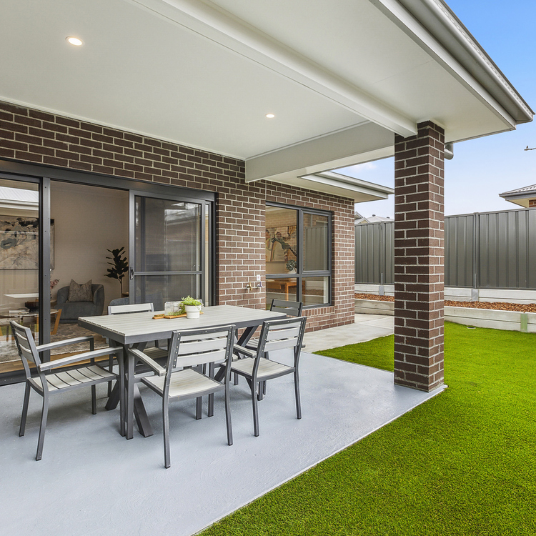 A tidy and inviting backyard patio with outdoor furniture and grass bed 