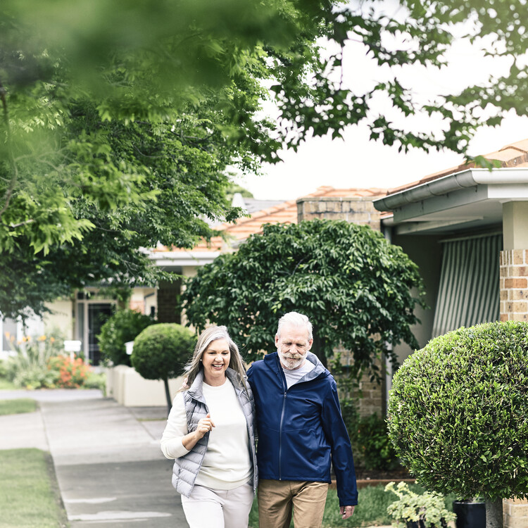 Couple walking with houses and trees behind them 