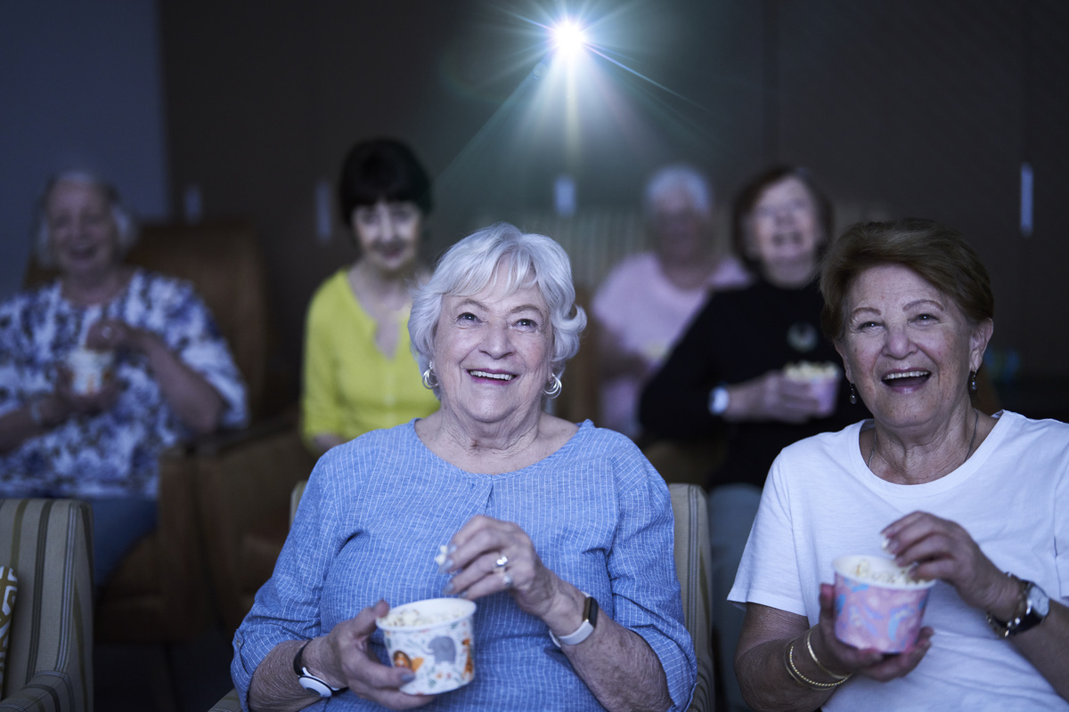 Residents enjoying a movie in the village theatre while eating popcorn