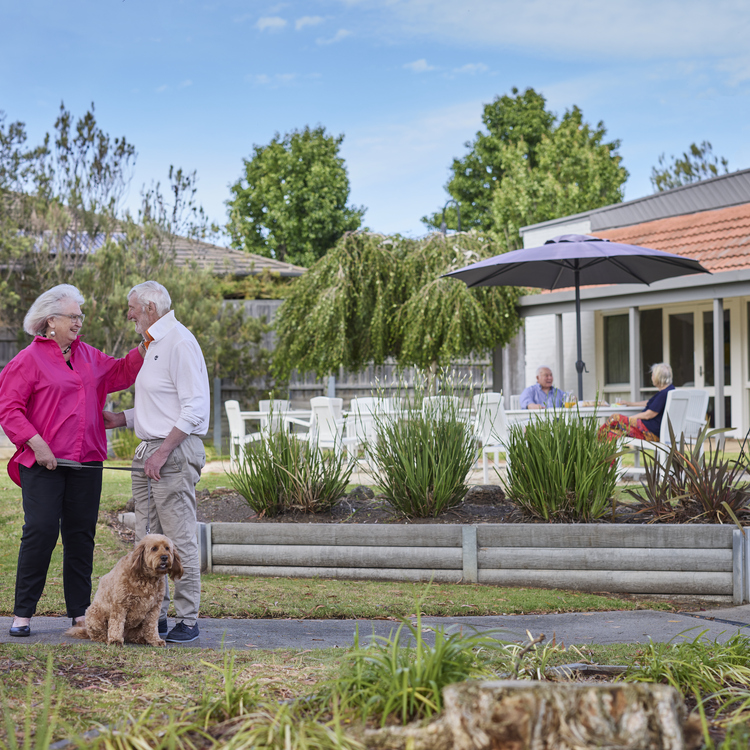 A couple with a dog standing in front of a villa at Koorootang Court retirement village