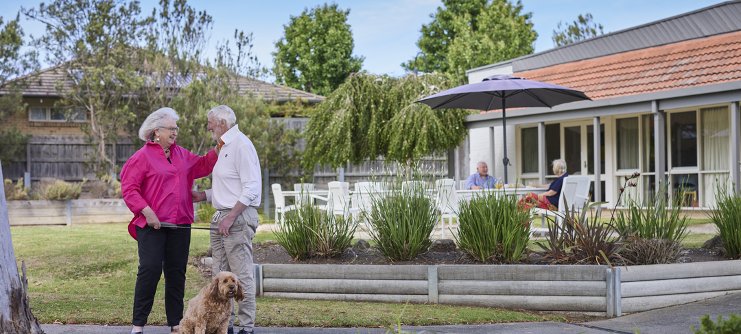 A couple with a dog standing in front of a villa at Koorootang Court retirement village