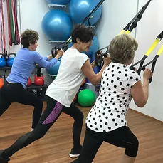 Three older women using fitness equipment at Community Moves, a gym for seniors and older adults.
