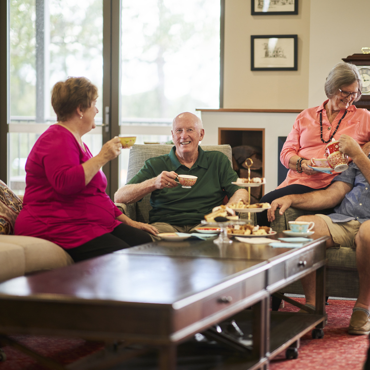Four residents sitting in the community centre and having afternoon tea