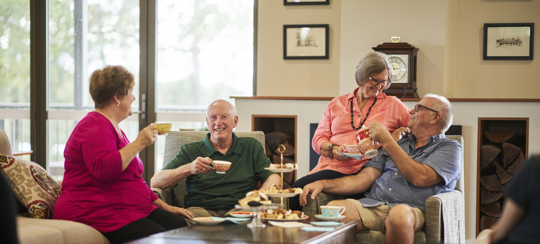 Four residents sitting in the community centre and having afternoon tea