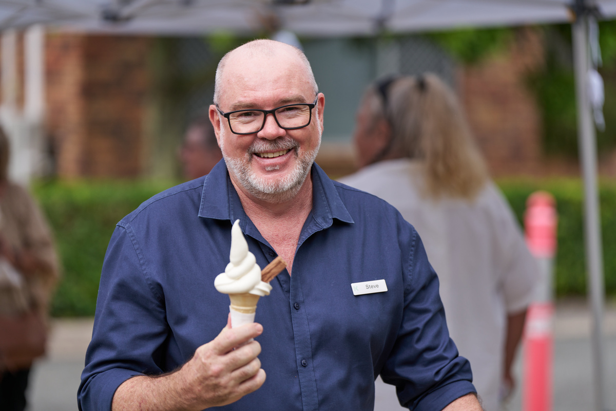 A staff member of a retirement village smiling and holding up an ice cream