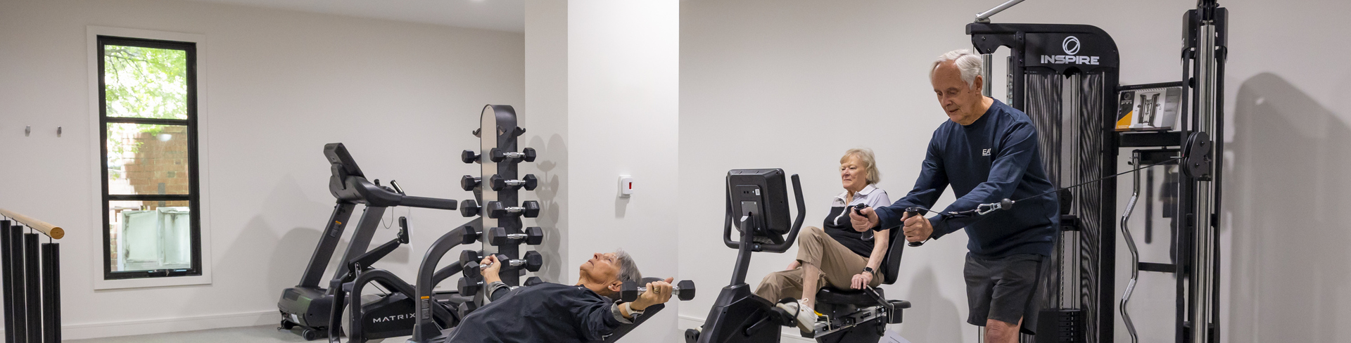 Three older adults working out in a gym at a retirement village