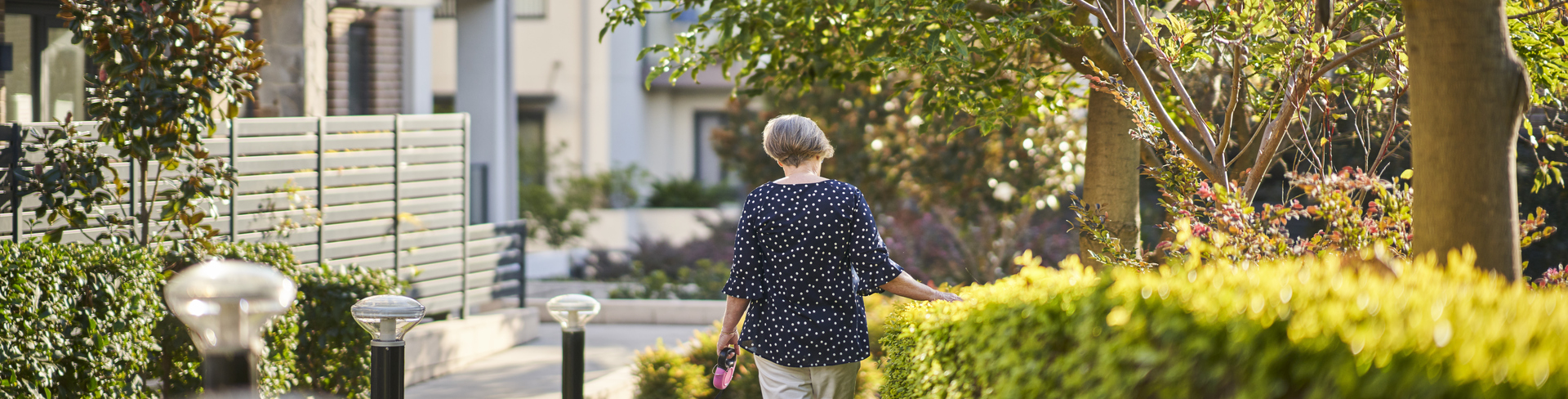 An elderly lady walking her dog outside her retirement village