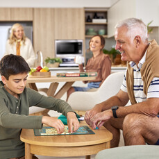 A retirement village resident is playing a board game with his grandson