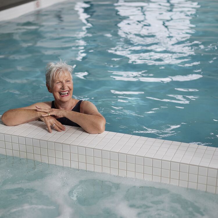 A woman swimming in an indoor pool smiling
