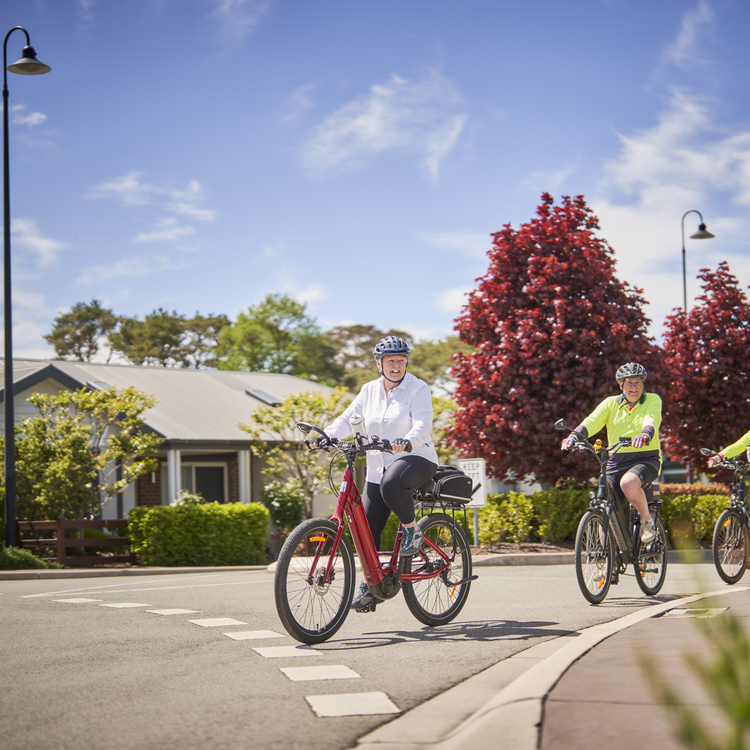Three retirement village residents riding bikes through their village