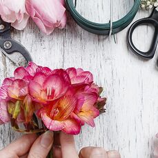 A florist hands cutting flowers on the desk with scissors and plants around