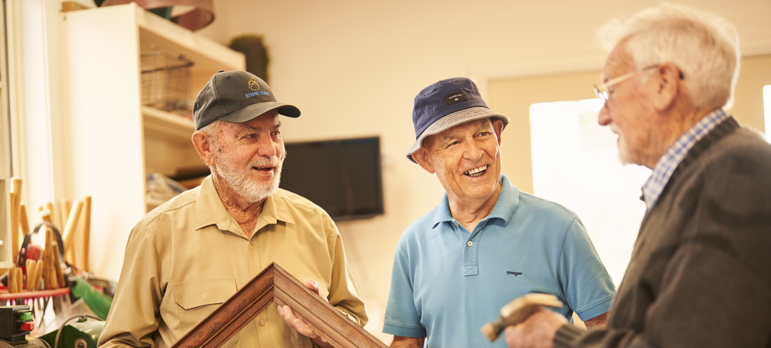 Three residents holding a wooden frame and a hammer discussing their handy work