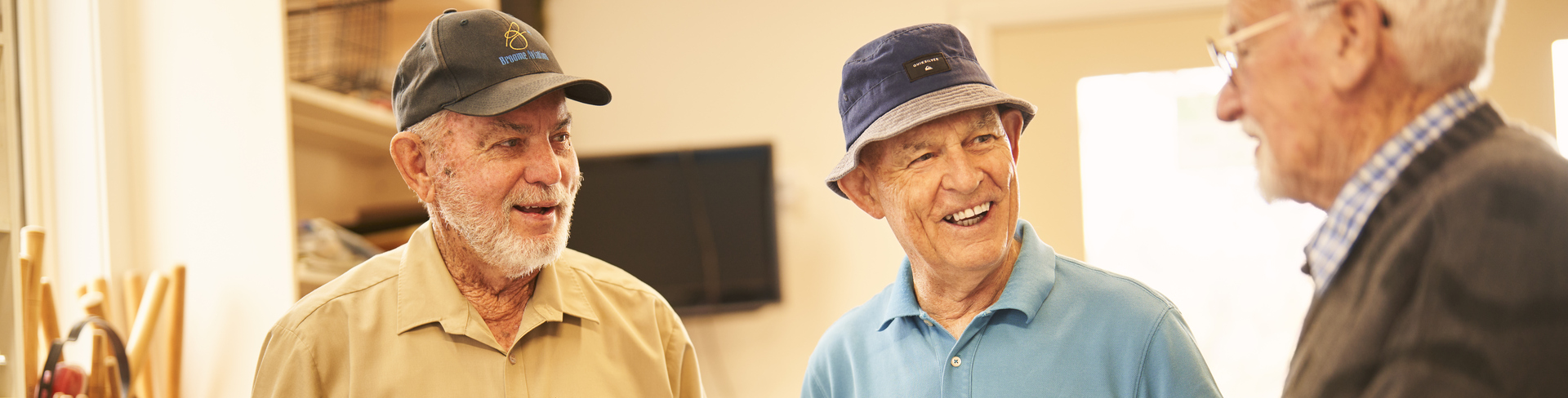 Three residents holding a wooden frame and a hammer discussing their handy work