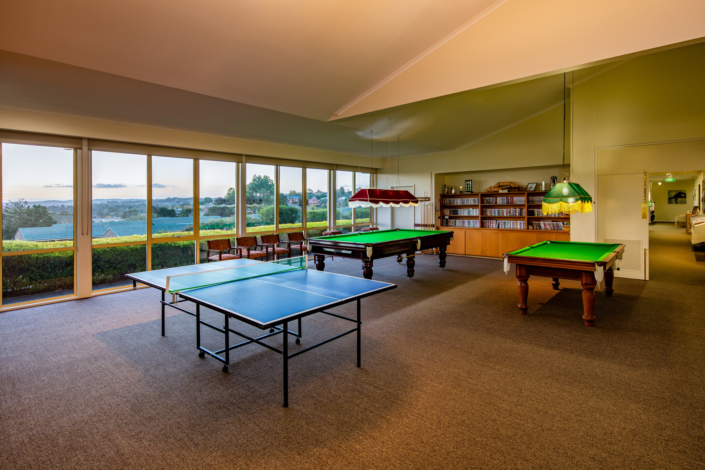 Meadowvale Village two pool tables and table tennis game area with bookcase on wall