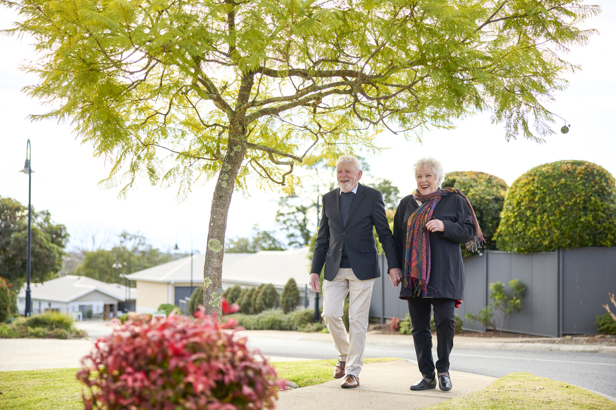 a senior couple holding hands and walking in a retirement village