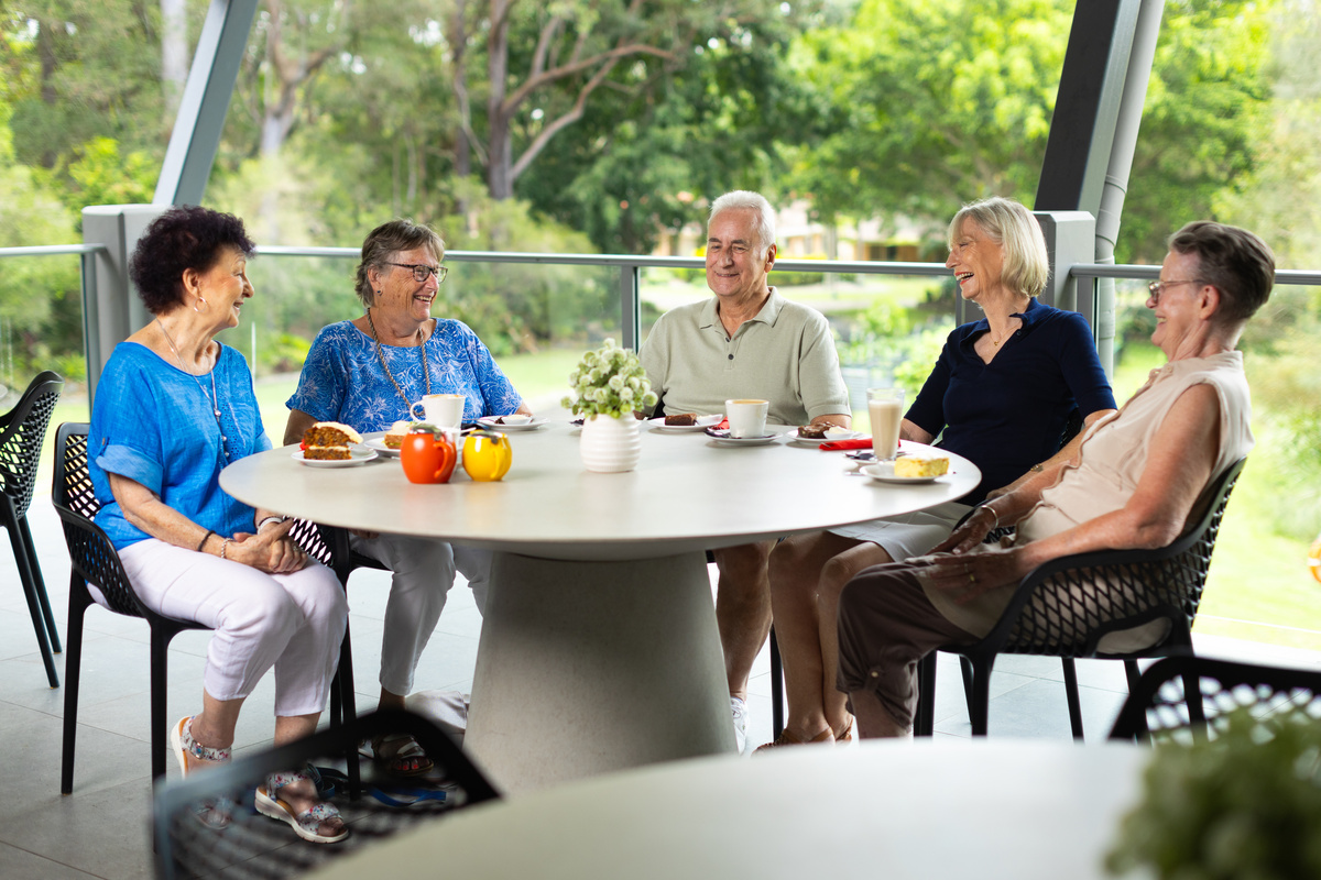 A group of seniors chatting and laughing over morning tea