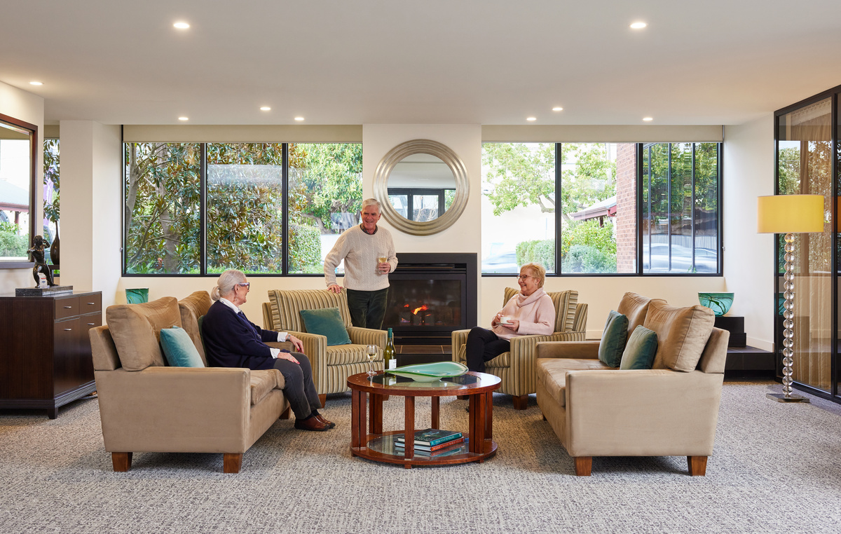 The Brighton on Bay people socialising around fireplace on comfortable couches