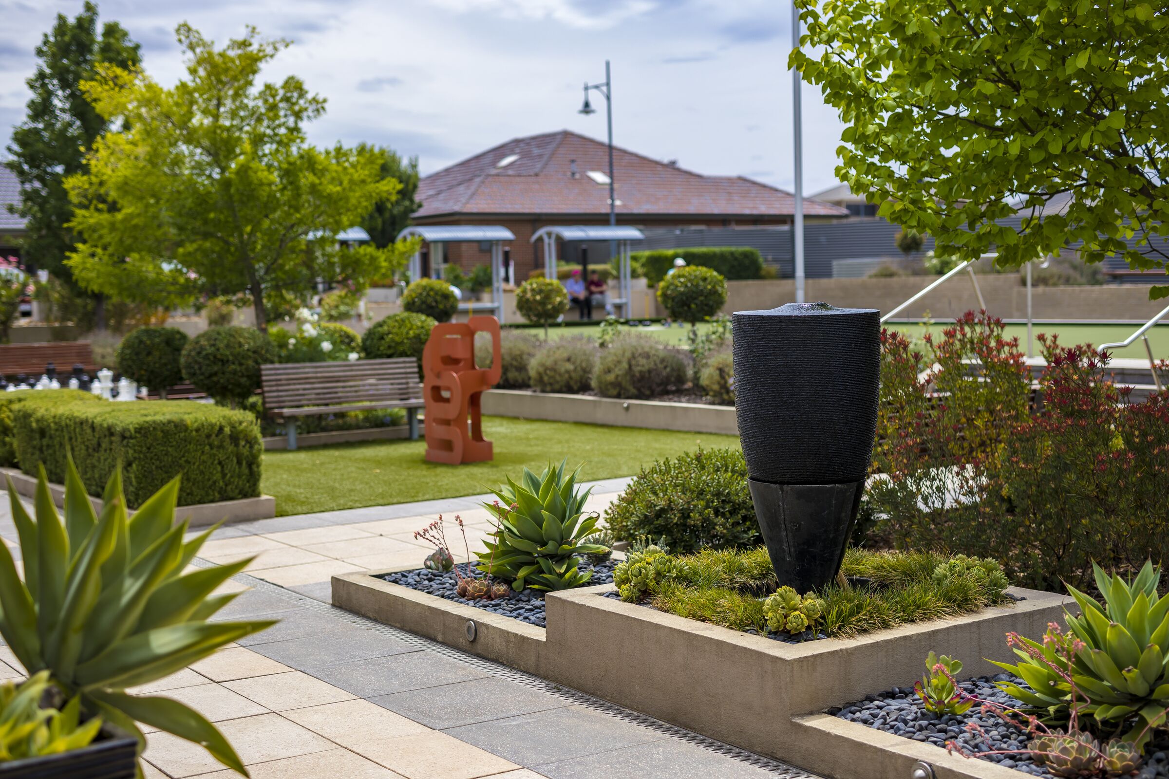 Caesia Gardens landscaping with modern statue artwork, distant outdoor chess and bowling green