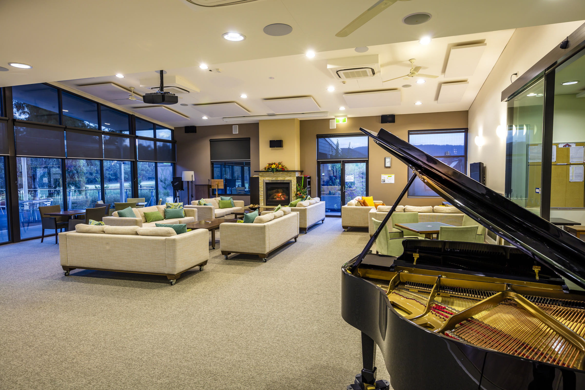 Waterford Park lounge area with fireplace next to outdoor terrace, piano in foreground