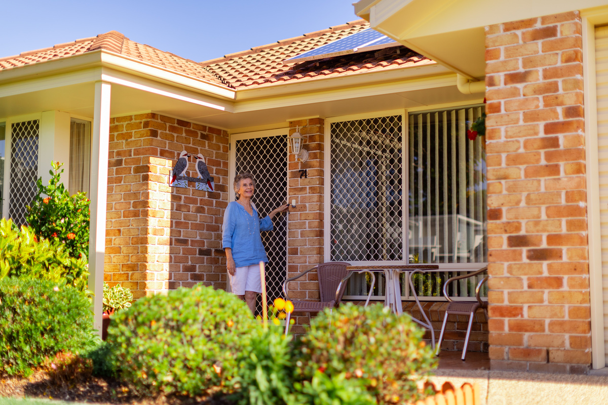 A senior woman stepping out and closing the door of her home behind her
