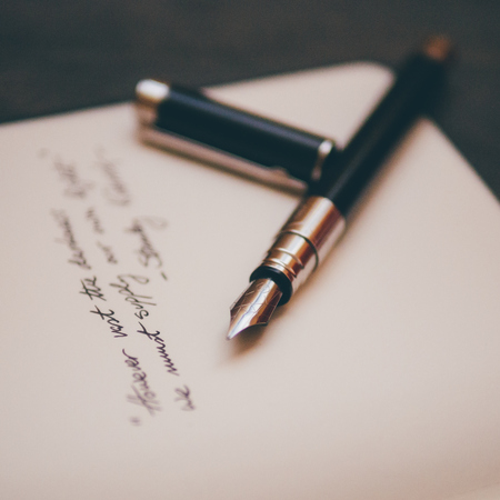 Black and silver fountain pen lying on a piece of paper with a poem written on it