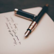 Black and silver fountain pen lying on a piece of paper with a poem written on it