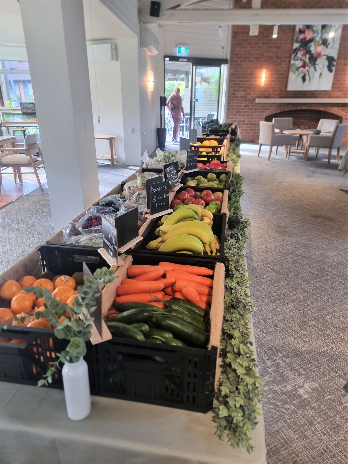 A pop-up stall table featuring fresh vegetables and fruits in the communal area of the retirement village Trebartha by Ardency