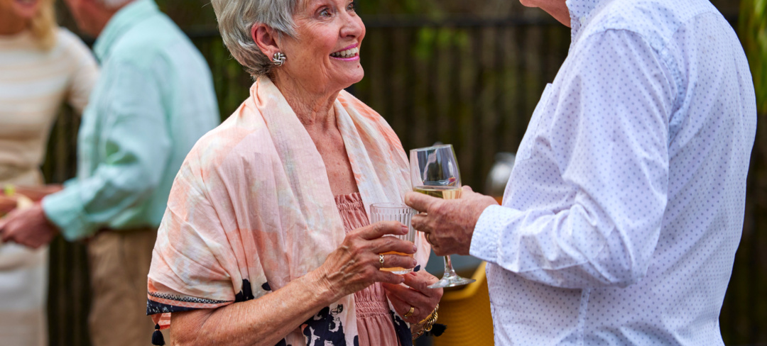 Residents of a retirement village having a chat over drinks outside on a terrace