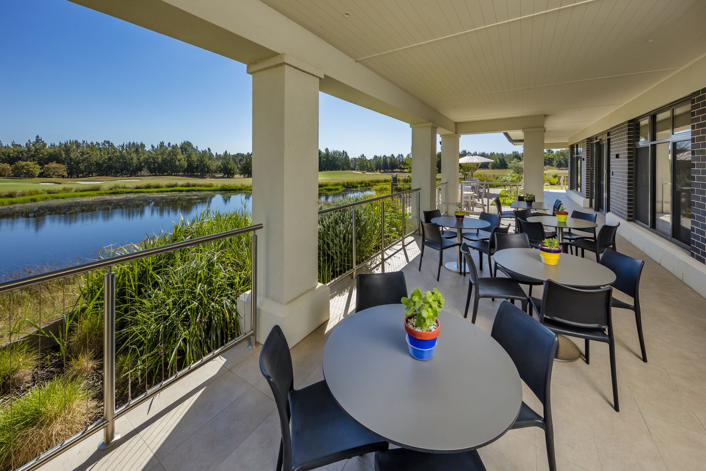 The Links at Waterford covered terrace with seating overlooking golf course lake