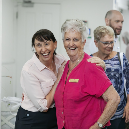 A staff member and a resident looking at the camera having a good time and laughing.