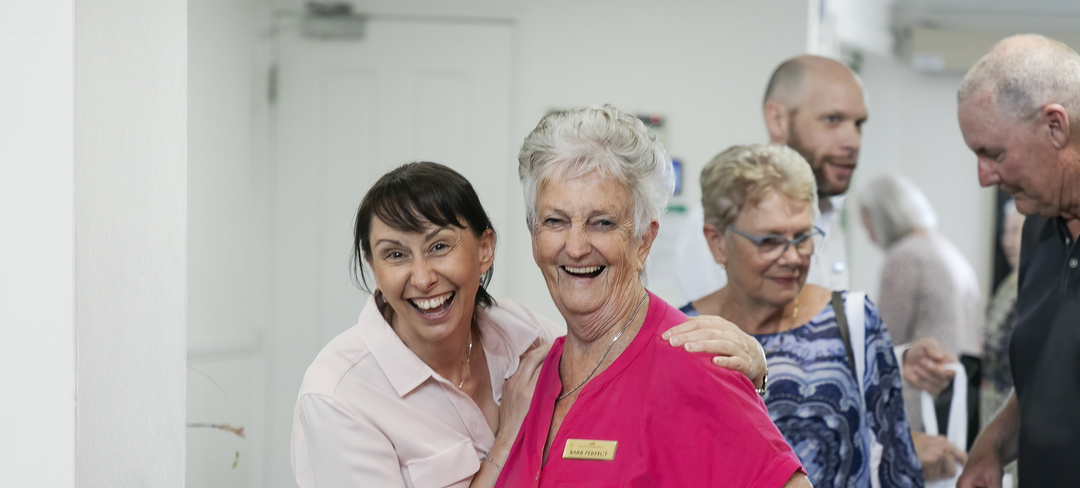 A staff member and a resident looking at the camera having a good time and laughing.