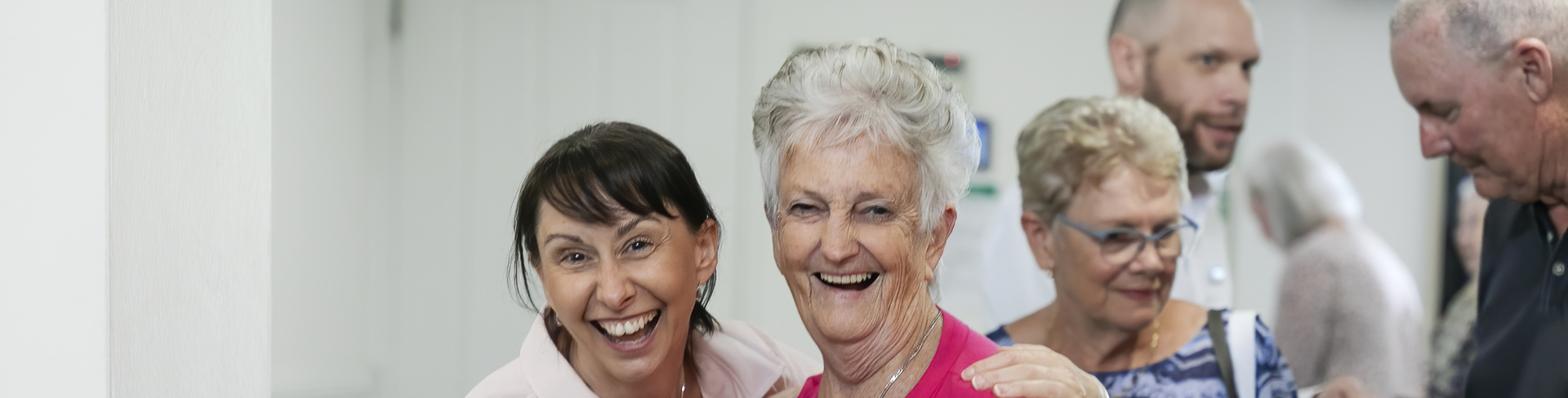 A staff member and a resident looking at the camera having a good time and laughing.