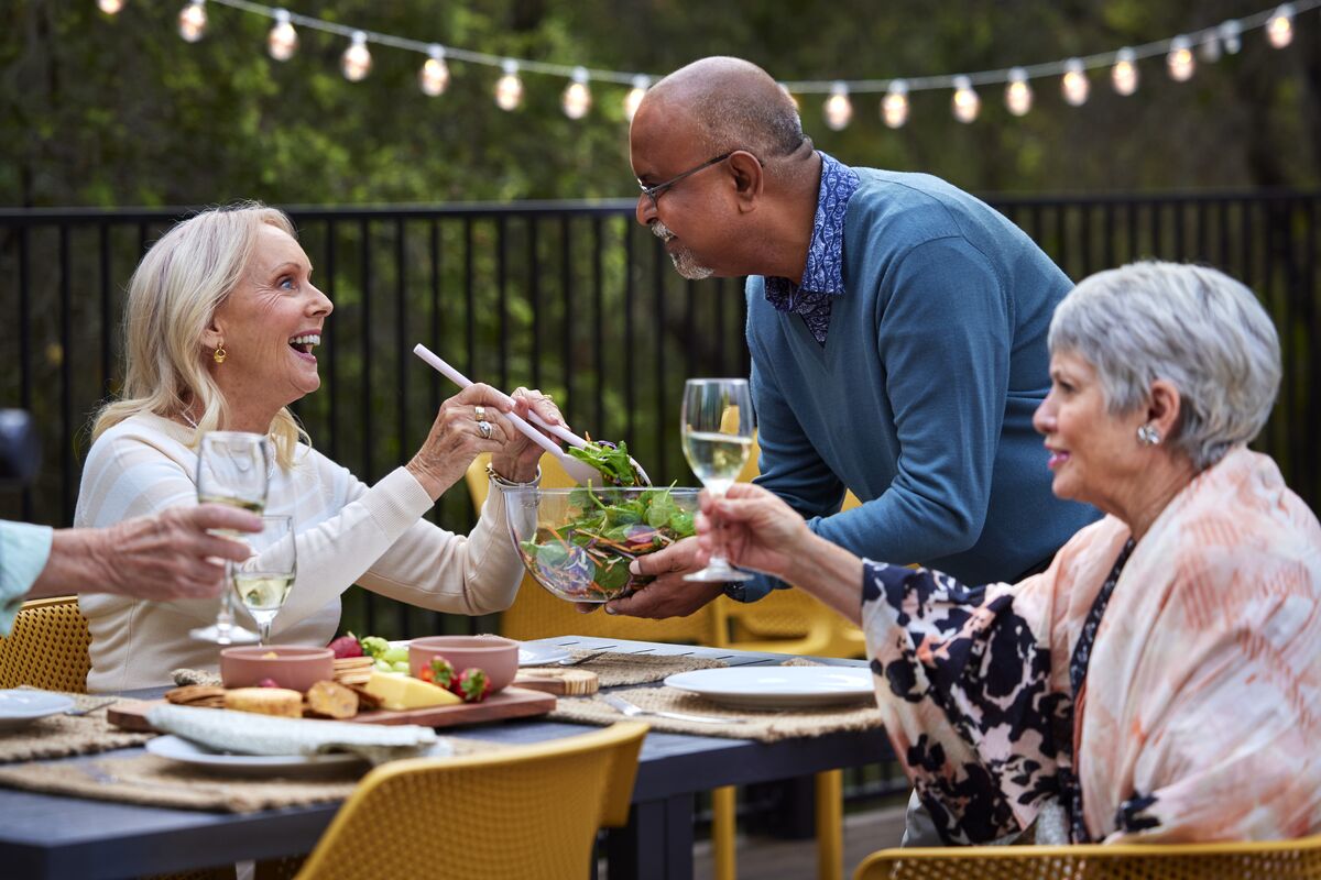 Retirement village residents having dinner together outside in the gardens