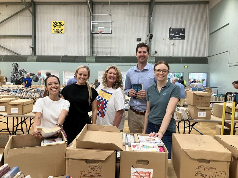 Five people smiling surrounded by boxes of books
