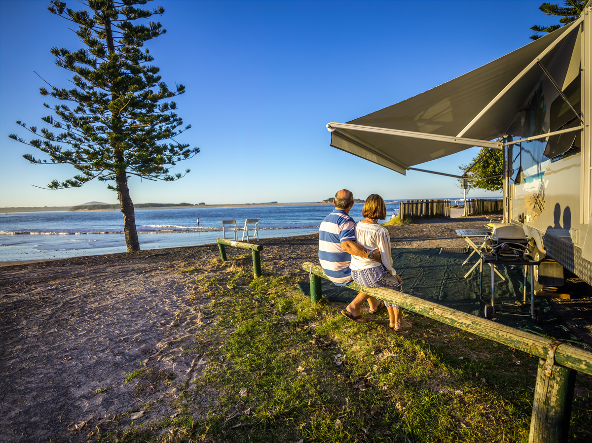 A retired couple sitting in a caravan park looking out over the ocean