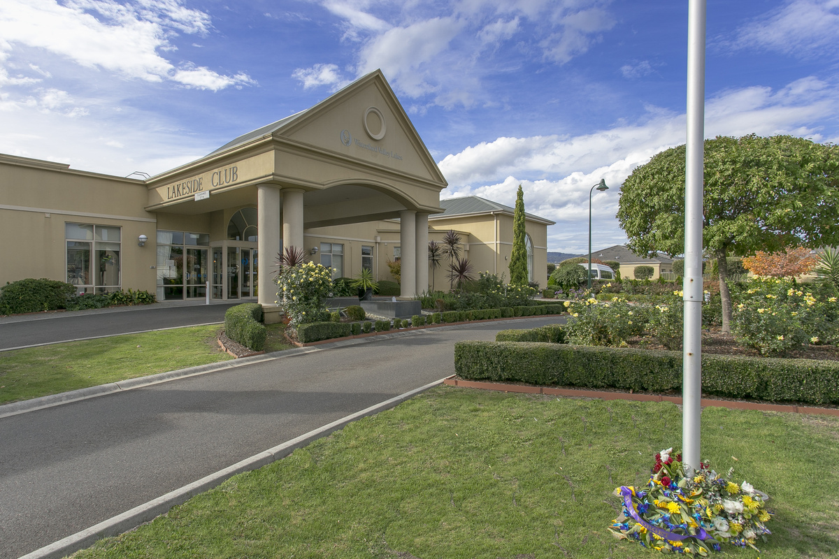 Waterford Valley Lakes main entrance outside with landscaped garden, road and flag pole