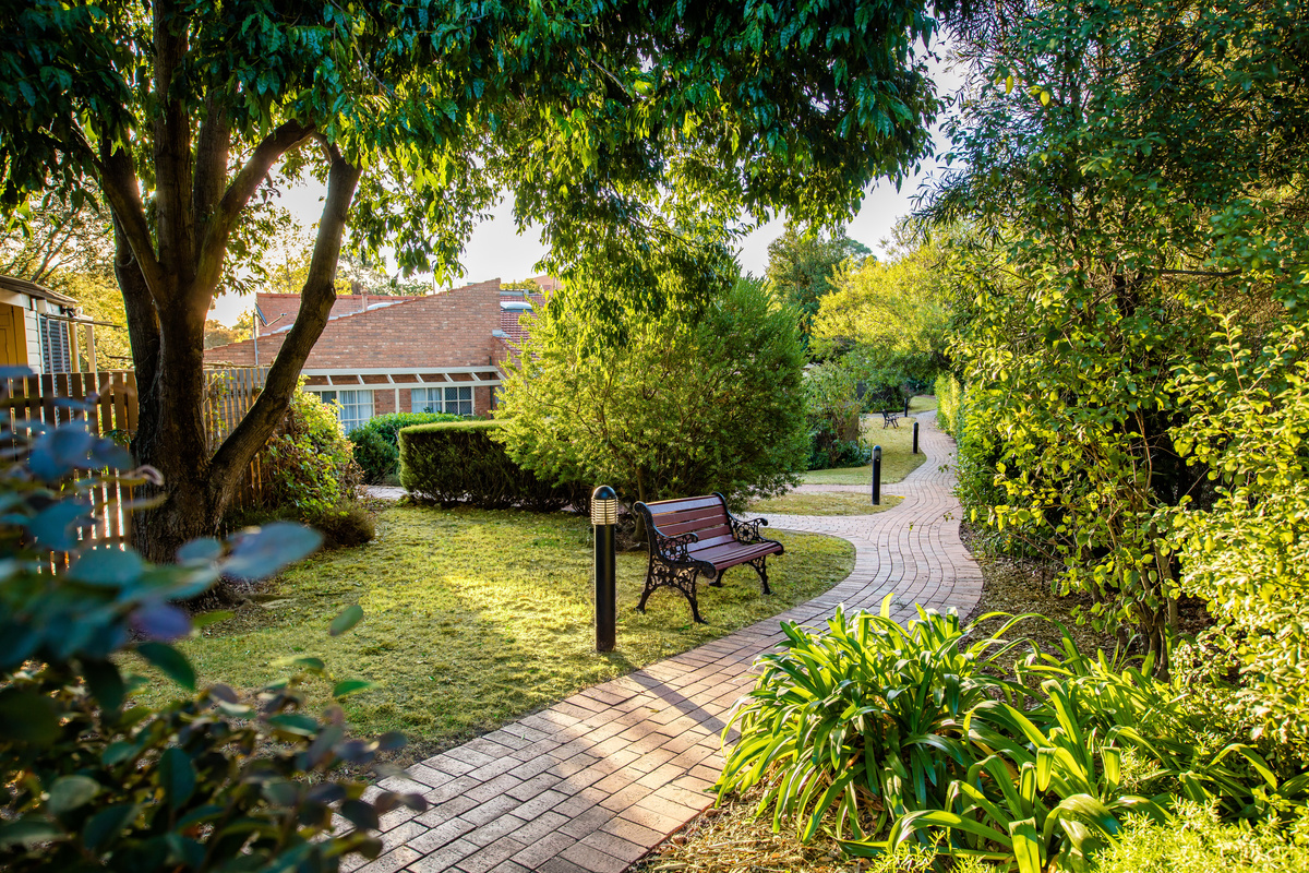 Fiddlers Green pathway by building and trees and a bench seat