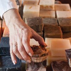 A close-up of hands placing handmade soaps in a display. 