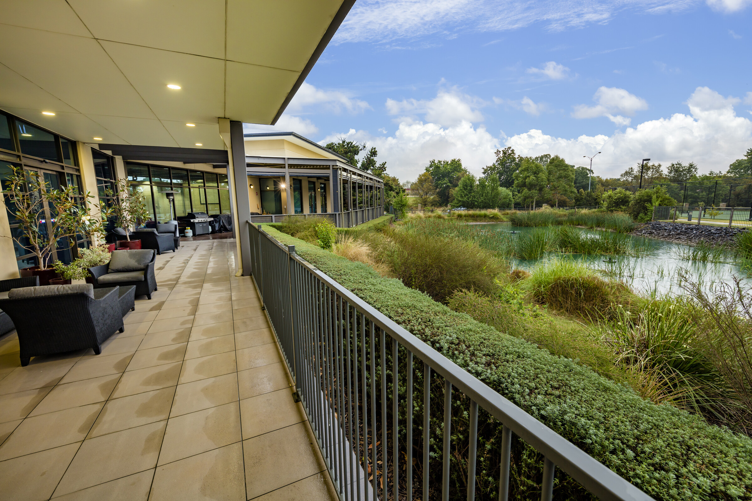 Woodlands Park covered terrace with seating beside main building overlooking pond