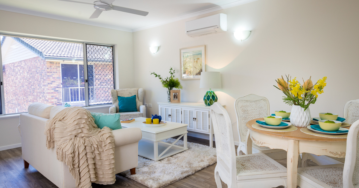 An open plan living and dining area with wooden floors and white walls.
