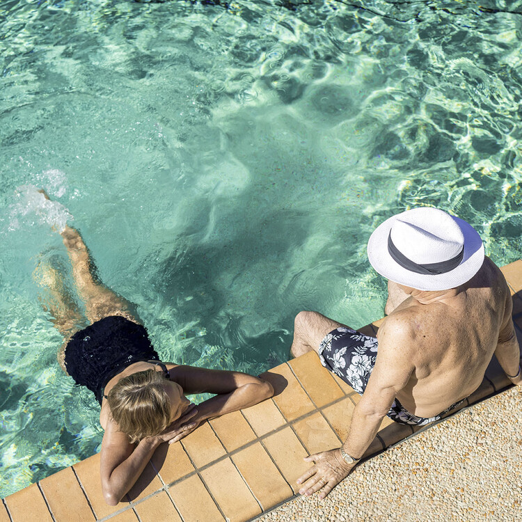 Couple relaxing in and beside an outdoor pool