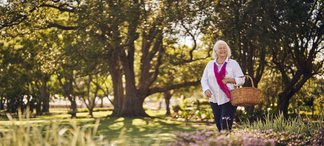 A smiling lady with a basket walking through Closebourne Retirement Village