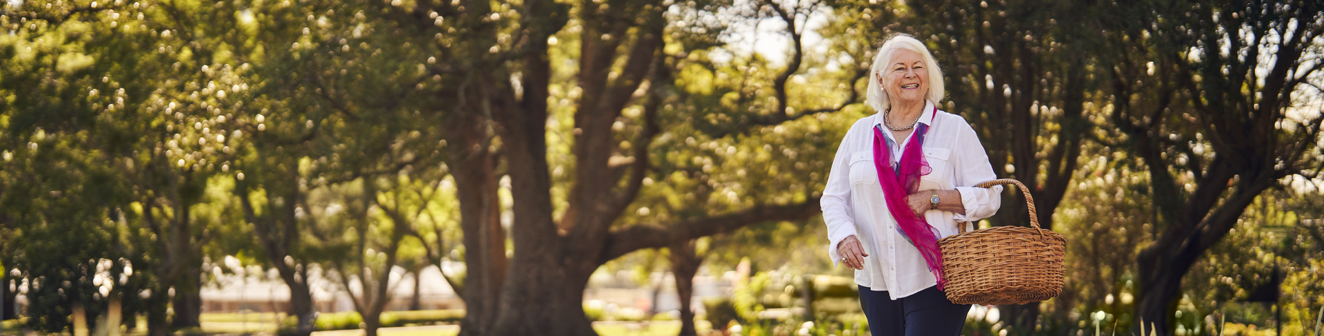 A smiling lady with a basket walking through Closebourne Retirement Village