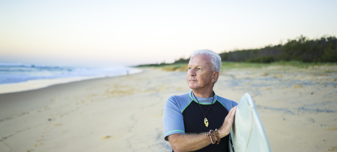A hi-res pic of a man and carrying his surfboard on the beach