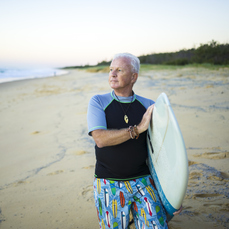 A hi-res pic of a man and carrying his surfboard on the beach
